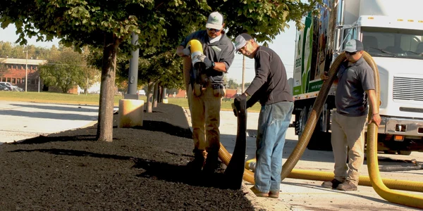 Two men working together to handle a large hose outdoors.